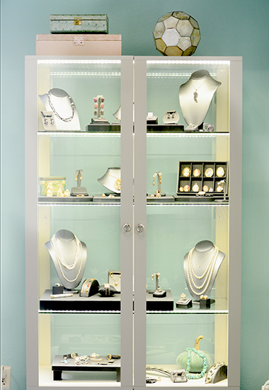 A selection of jewelry in a lighted glass case for sale on consignment