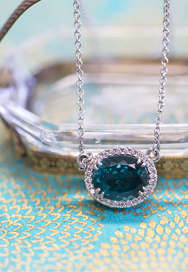 Large blue oval jewel pendant with small diamonds set in a circle around it, an example of the kind of jewelry EMS will purchase